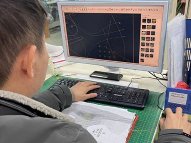 A developer working on a shoe pattern in CAD software on a desktop computer.