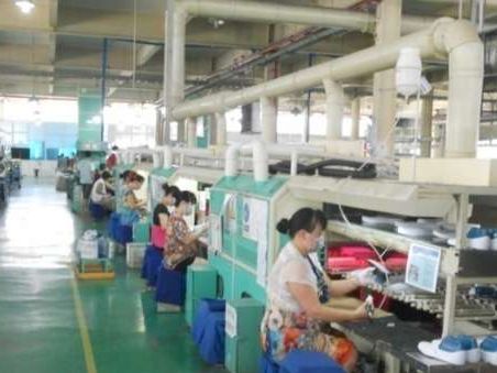 At one of our partner factories: workers along an assembly line in a bright green-floored factory hall.