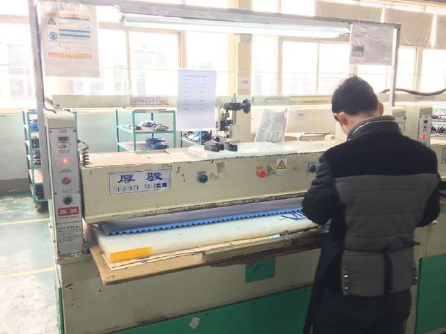 At one of our partner factories: a worker operating a cutting press on a production floor.